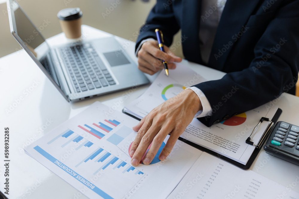 Asian businessman working at office with laptop, tablet and graph data sheet on his desk. Asian businessman working at office with laptop, tablet and graph data sheet on his desk.