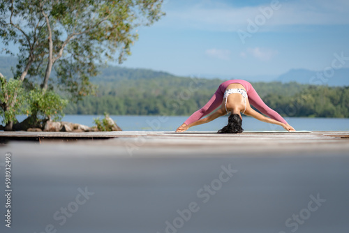 Beautiful attractive Asian woman practice fitness yoga pose on the pool above the Mountain peak in front of nature lake views, Feel so comfortable lifestyle and relax exercise in holiday morning © chokniti