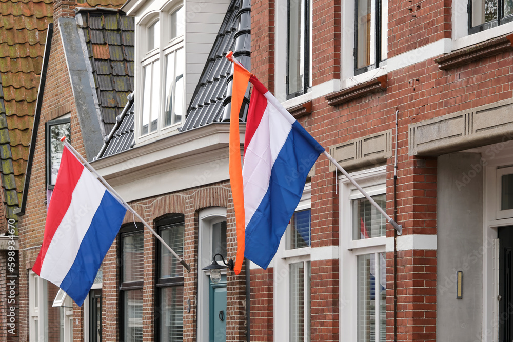 Dutch flags and orange streamer waving in a typical dutch street on Koningsdag. Koningsdag is a national holiday in the Kingdom of the Netherlands.