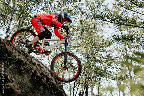Photography female racer cyclist riding steep descent downhill race in forest, summer mounta