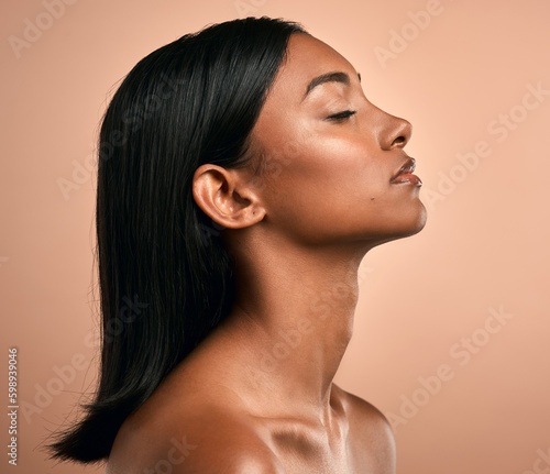 Love yours. Side shot of a beautiful young woman posing against a brown background.