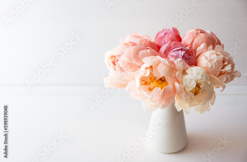 Fototapeta Naklejka Na Ścianę i Meble -  Beautiful bouquet of fresh coral peony flowers in full bloom in vase. Floral still life with blooming peonies. Negative space for text.