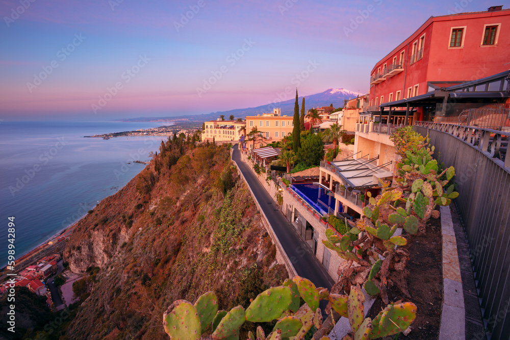 Taormina, Sicily, Italy. Cityscape image of picturesque town of Taormina, Sicily with volcano Mt. Etna in the background at sunrise.
