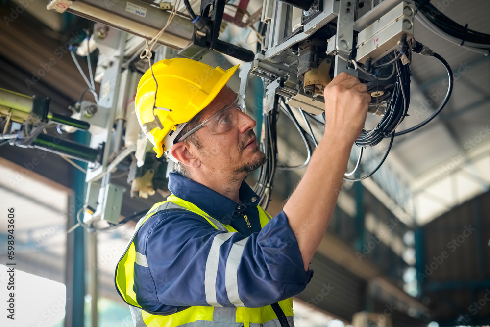 Male technician programs a robot arm with a digital tablet and assembly robot in a factory. Apprentice engineers programming robots in factory. Male technician programs a robot arm with a digital tablet and assembly robot in a factory. Apprentice engineers programming robots in factory.