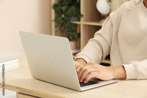African American man typing on laptop at wooden table indoors, closeup