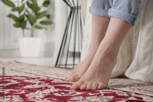 Woman on carpet with pattern at home, closeup. Space for text