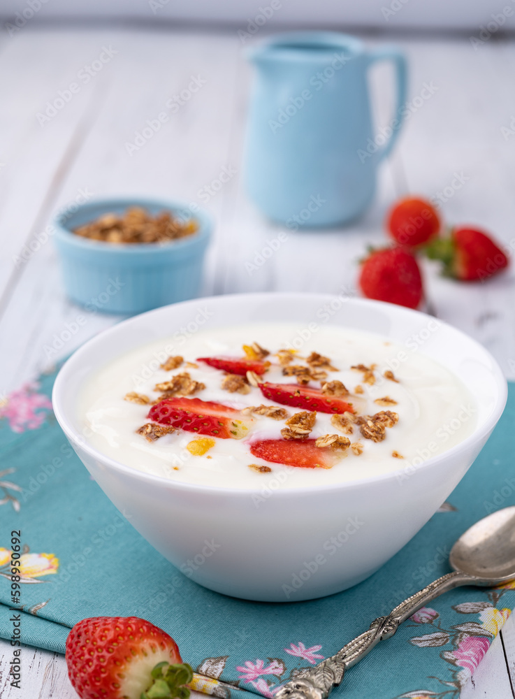 Yogurt with strawberry and granola in a bowl over white wooden table Yogurt with strawberry and granola in a bowl over white wooden table