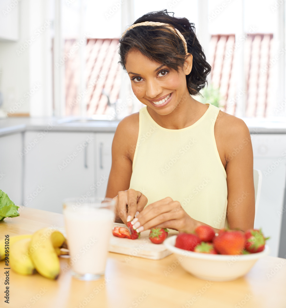 Strawberries make for the best smoothies. Portrait of a young woman slicing fruit in a kitchen. Strawberries make for the best smoothies. Portrait of a young woman slicing fruit in a kitchen.