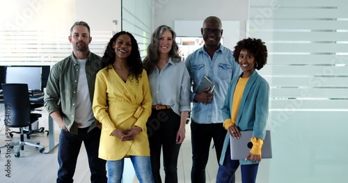 Smiling group of diverse businessmen and businesswomen standing side by side together in a bright modern office