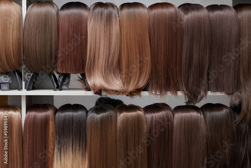 Fototapeta Showcase of natural looking wigs in different shades of brunette fixed on the wig holders in beauty salon