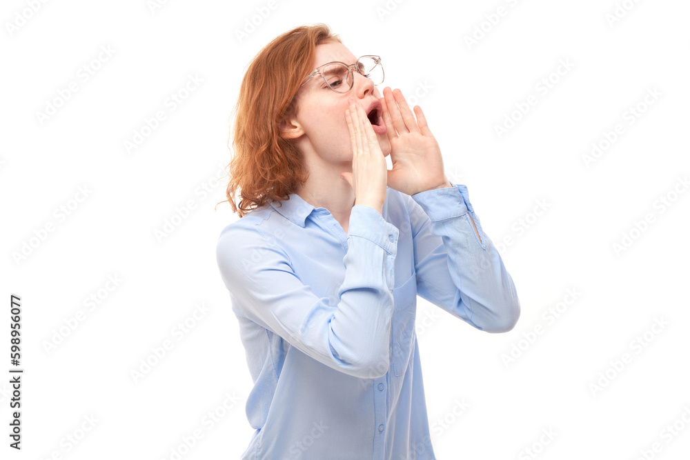 Portrait of redhead young woman screaming into her palms on white studio background. Important information, news concept Portrait of redhead young woman screaming into her palms on white studio background. Important information, news concept