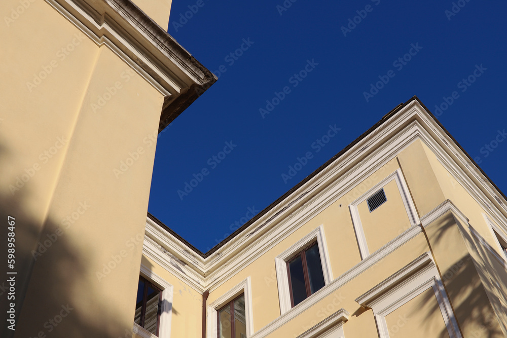 Urban architecture, building seen from below, yellow walls, blue sky in the background. Urban architecture, building seen from below, yellow walls, blue sky in the background.