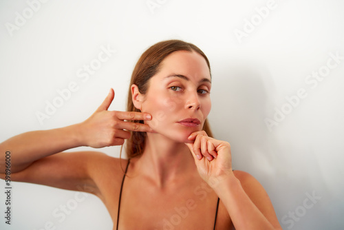 Foto retrato mujer joven caucasica practicando ejercicios de yoga facial en estudio