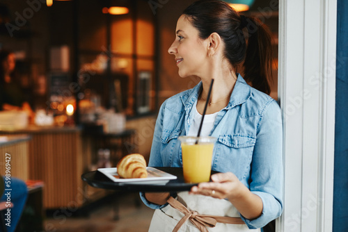 Smiling waitress carrying a food order to cafe customers