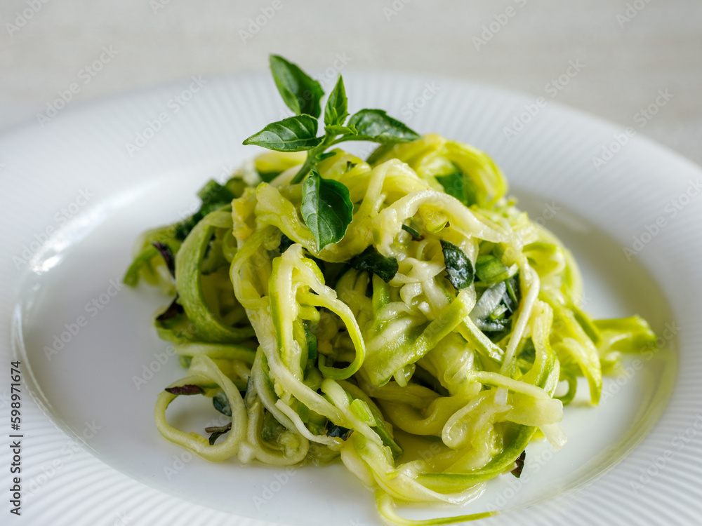 Salad of marinated raw zucchini spaghetti in spices and herbs. Vegan food. Healthy meal. Side view, close up Salad of marinated raw zucchini spaghetti in spices and herbs. Vegan food. Healthy meal. Side view, close up
