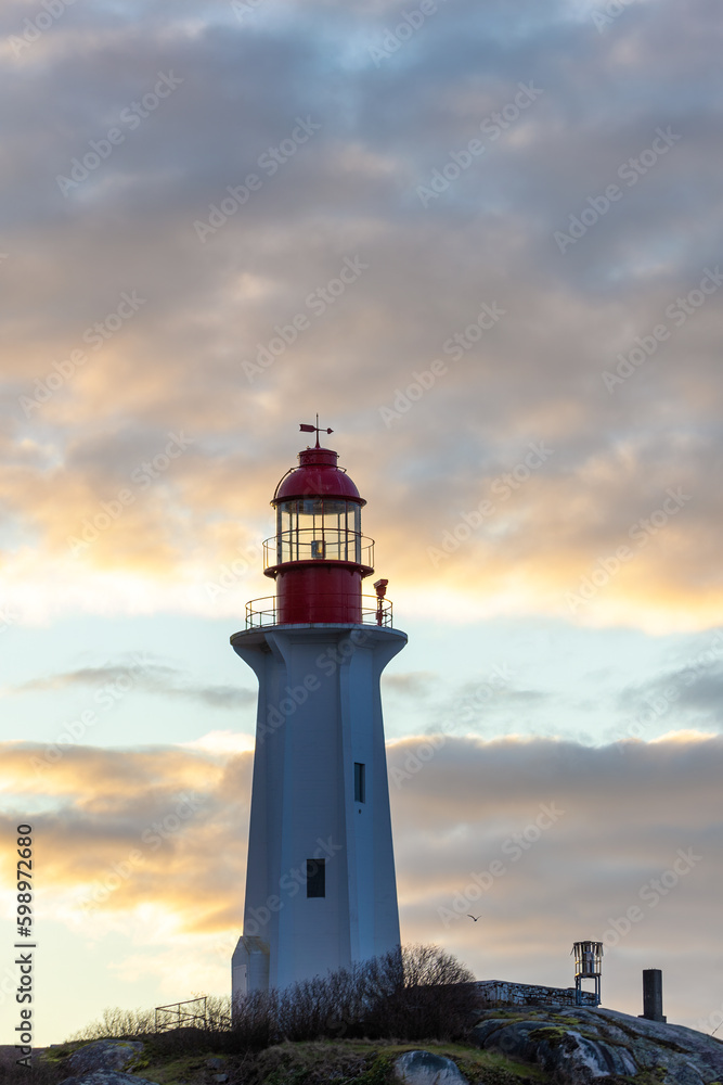 Sunrise over a tall lighthouse situated on a rugged rocky coast - Point Atkinson Lighthouse Park, Vancouver 