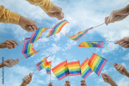diversity people hands raising colorful lgbtq rainbow flags together , a symbol for the LGBT community
