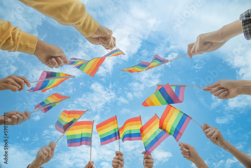 Diversity people hands raising colorful lgbtq rainbow flags together , a symbol for the LGBT community