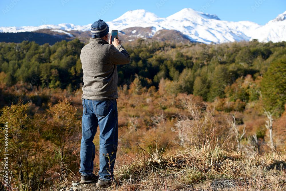 Senior adult seen from behind enjoying the landscape formed by the snowy mountains