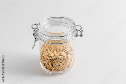 food, healthy eating and diet concept - jar with oat flakes on white background