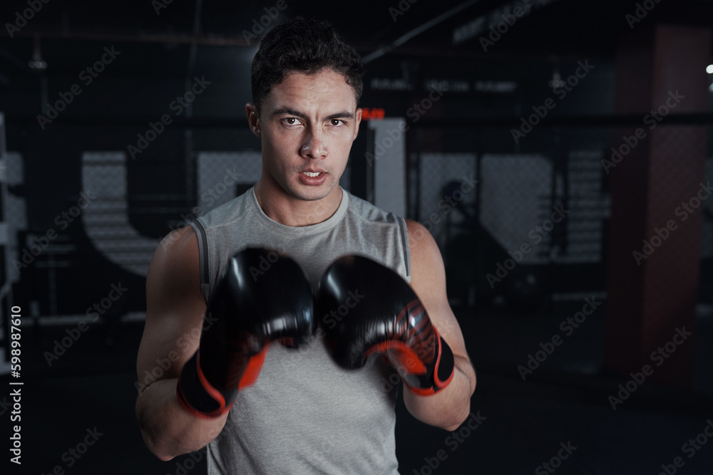 Box your way to a stronger body. Portrait of a young man practicing his boxing routine at a gym.