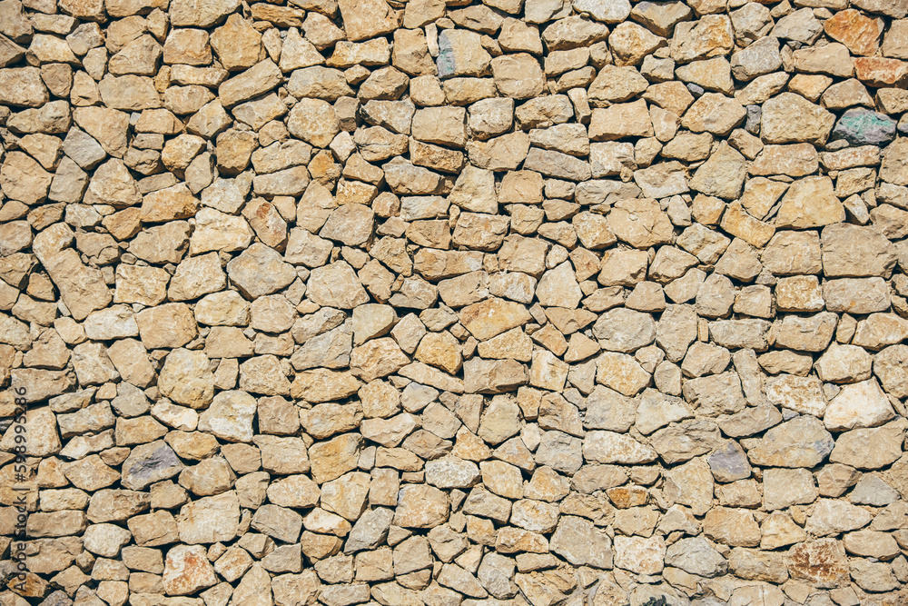 Masonry wall of natural brown stones with irregular pattern texture background. Typical masonry wall in Spain Masonry wall of natural brown stones with irregular pattern texture background. Typical masonry wall in Spain