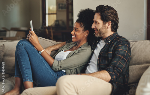 Theres an app for everything nowadays. a happy young couple using a digital tablet together while relaxing on a couch at home.