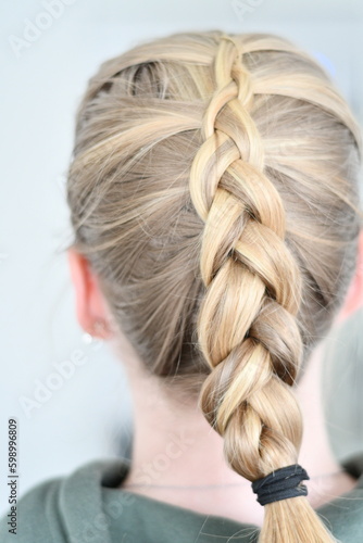 Back view of blond caucasian woman with braided hair. Blond highlights in long hair with beautiful hairstyle.