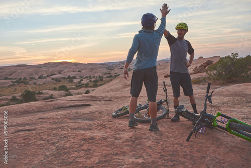 That was a good ride. two men giving each other a high five while out mountain biking. photo