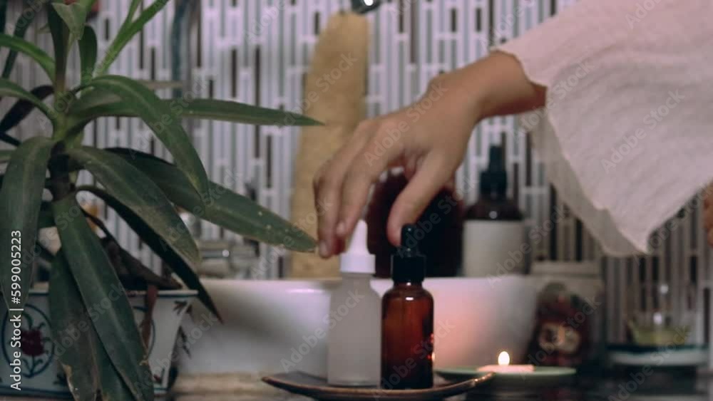 Woman applying organic eco-friendly skincare serum from a glass bottle dropper as a part of a night healthy self-care routine showing wellness, wellbeing and balance healthy lifestyle