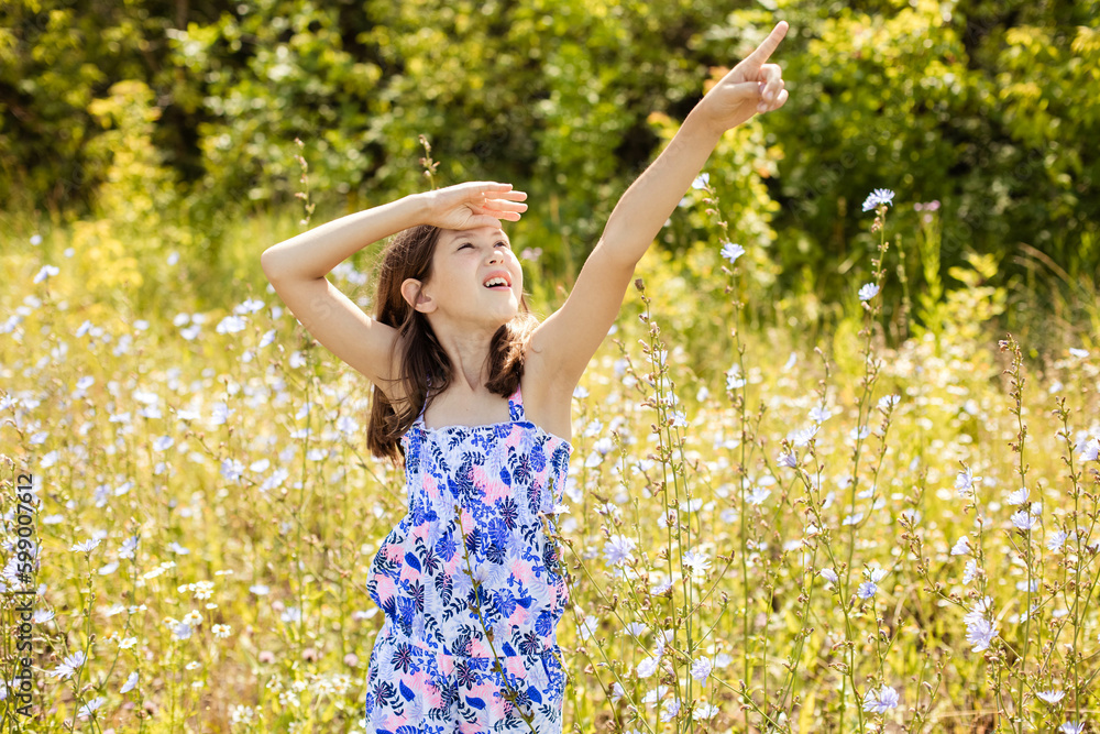 Teenage girl looking at the sky and pointing her hand up in a summer park Teenage girl looking at the sky and pointing her hand up in a summer park