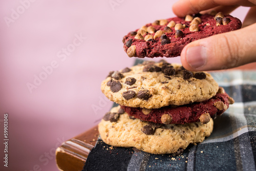 Hand taking red chocolate cookie with chips on wooden table