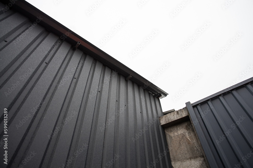 Geometric industrial dark composition of a concrete gray wall and an iron corrugated roof of a building, background for your design or illustrations. Geometric industrial dark composition of a concrete gray wall and an iron corrugated roof of a building, background for your design or illustrations.