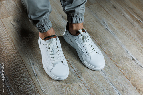 Men s summer shoes. Close-up of male legs in white leather sneakers. Collection of men s leather shoes