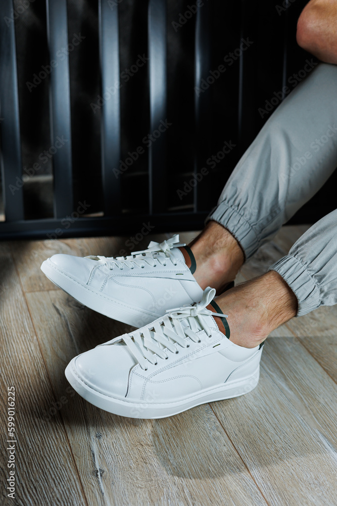 Close-up of male feet in shoes. A young man is standing in leather stylish  white sneakers in gray jeans. Summer men's shoes. Casual street style.  Stock Photo | Adobe Stock
