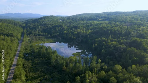 4K Aerial Drone Fly Toward Lake over Mountain Forest on Summer Day. Rise at end