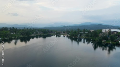 4K Aerial Drone video of Lake Placid in Summer at Sunrise with Swimmer. Orbit arc camera motion. Clouds and mountains visible