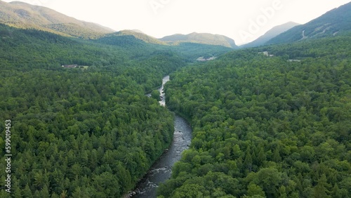 4K Aerial Drone Rise over turbulent creek water . Mountains visible in distance
