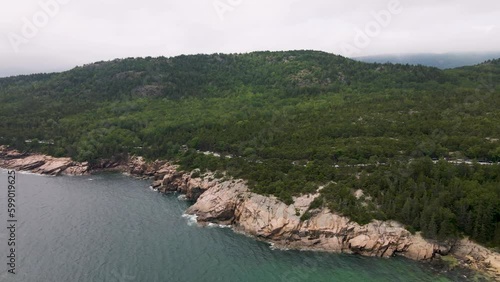 4K Aerial Drone Orbit Arc through Clouds over Pine Tree Peninsula. Water, Trees, Rocks, Coast visible