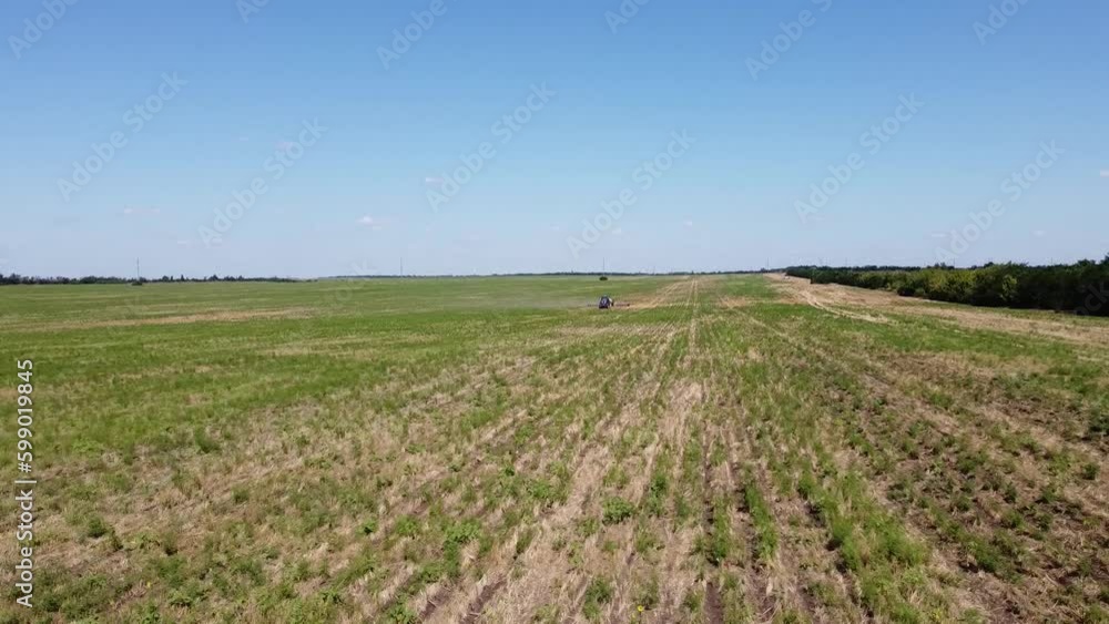 Blue tractor planting canola O.A. on no till field Blue tractor planting canola O.A. on no till field
