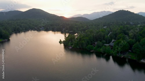 4K Aerial Drone video of Lake Placid in Summer at Sunrise with Swimmer. Reflection of sunrise in lake