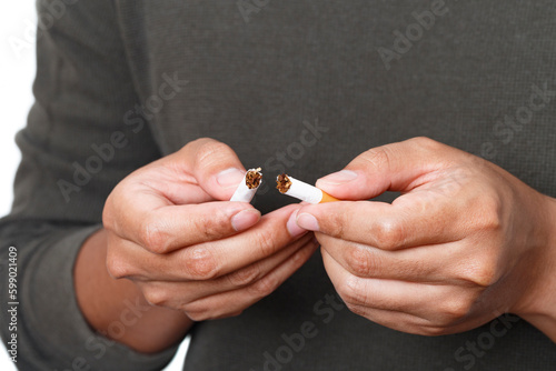 Man holding broken cigarette in hands. Stop smoking cigarettes concept. No smoking campaign concept.