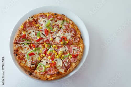Pizza with mushrooms, sweet peppers, corn, pepperoni and cheese on white table, top view