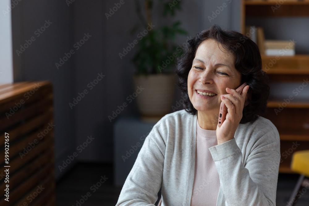 Happy middle aged senior woman talking on smartphone with family friends. Older mature lady with cell phone chatting with grown up children, resting in at home. Older generation modern tech usage Happy middle aged senior woman talking on smartphone with family friends. Older mature lady with cell phone chatting with grown up children, resting in at home. Older generation modern tech usage