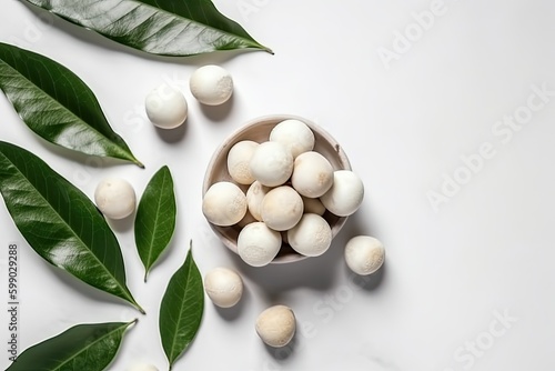 Top view of peeled macadamia nuts in a small plate next to the leaves on a white background. Generative AI