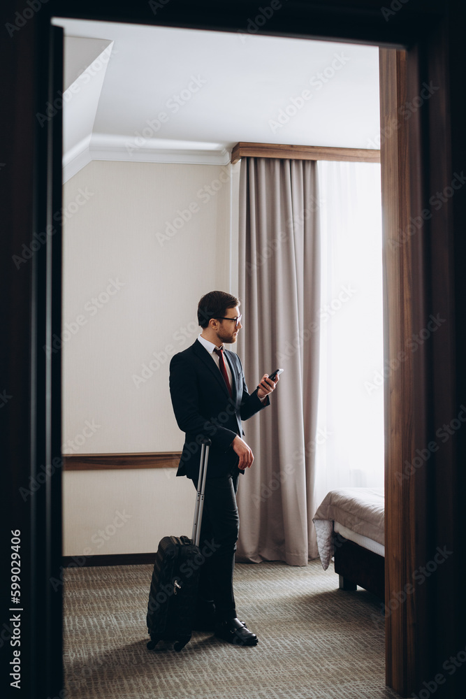 Fototapeta premium Back view of young elegant business traveler in formalwear entering comfortable hotel room in the morning