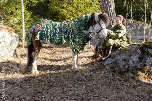 Camouflaged icelandic horse and woman in Finnish spring enviroment