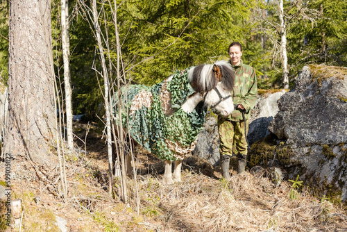 Camouflaged icelandic horse and woman in Finnish spring enviroment