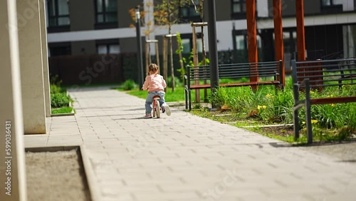 Wallpaper Mural Little girl riding balance bike in the courtyard of the residence in Prague, Europe Generative AI Torontodigital.ca