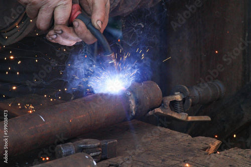 Service man welds old muffler to the car using argon welding